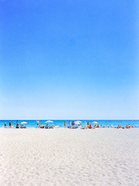 Fine art picture showing a beach with people sun tanning and watching the sea